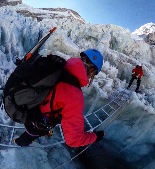 Masha crossing a ladder over a crevasse in Khumbu Icefall, Everest 